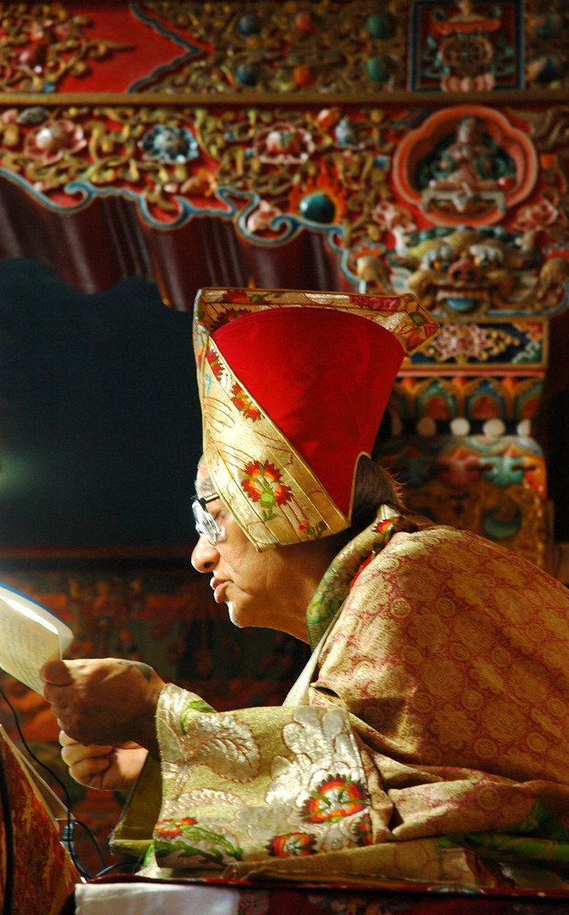 The Living Dharma Series: Bringing Tibetan Philosophy to the YouTube Generation - Transmission on the Triple Tantra: His Holiness Jigdal Dagchen Sakya reading a pecha, wearing formal silk robes, on his teaching throne, Tharlam Monastery of Tibetan Buddhism, Boudha, Kathmandu, Nepal